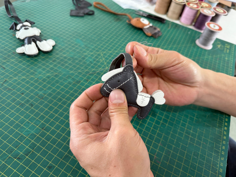 Premium handcrafted leather bag charms displayed beside artisan leather tools