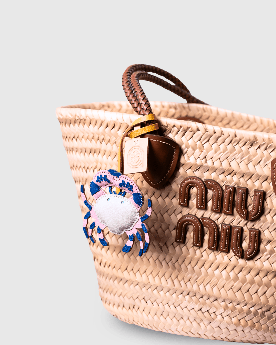 Straw tote bag with crab charm.