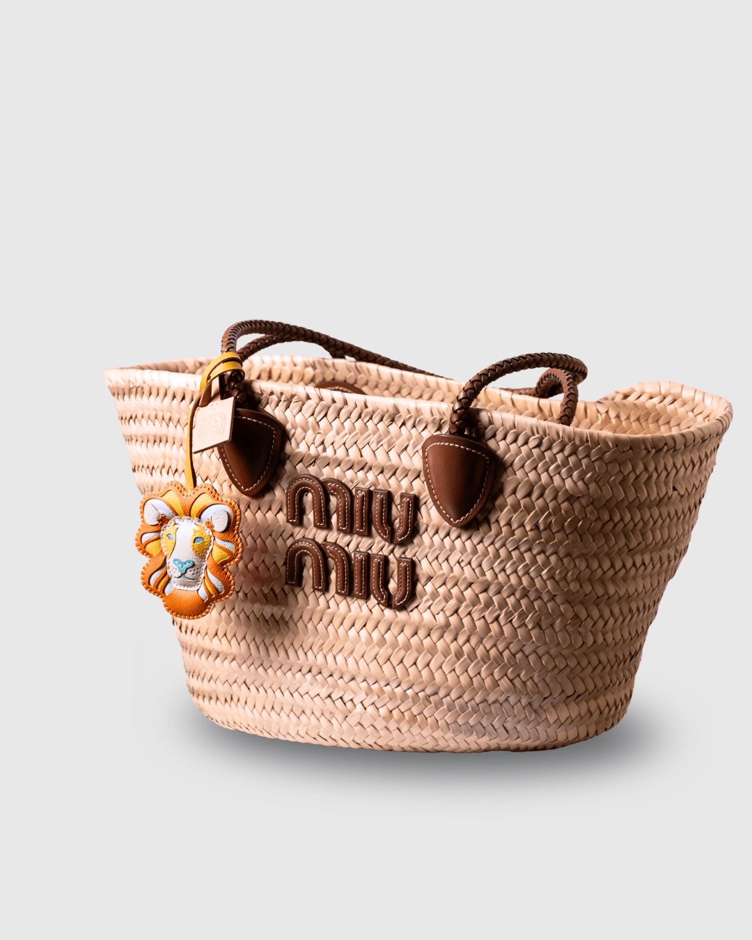 Straw tote bag with MIU MIU logo and lion charm.