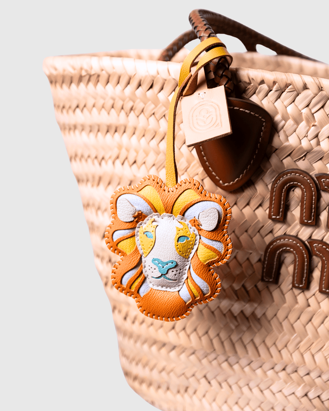 Woven straw bag with lion charm.