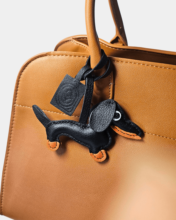Brown handbag with dachshund charm.