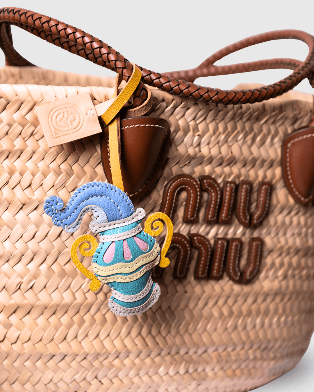 Straw tote bag with charm and logo.