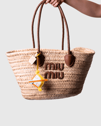Straw tote bag with brown handles and logo.