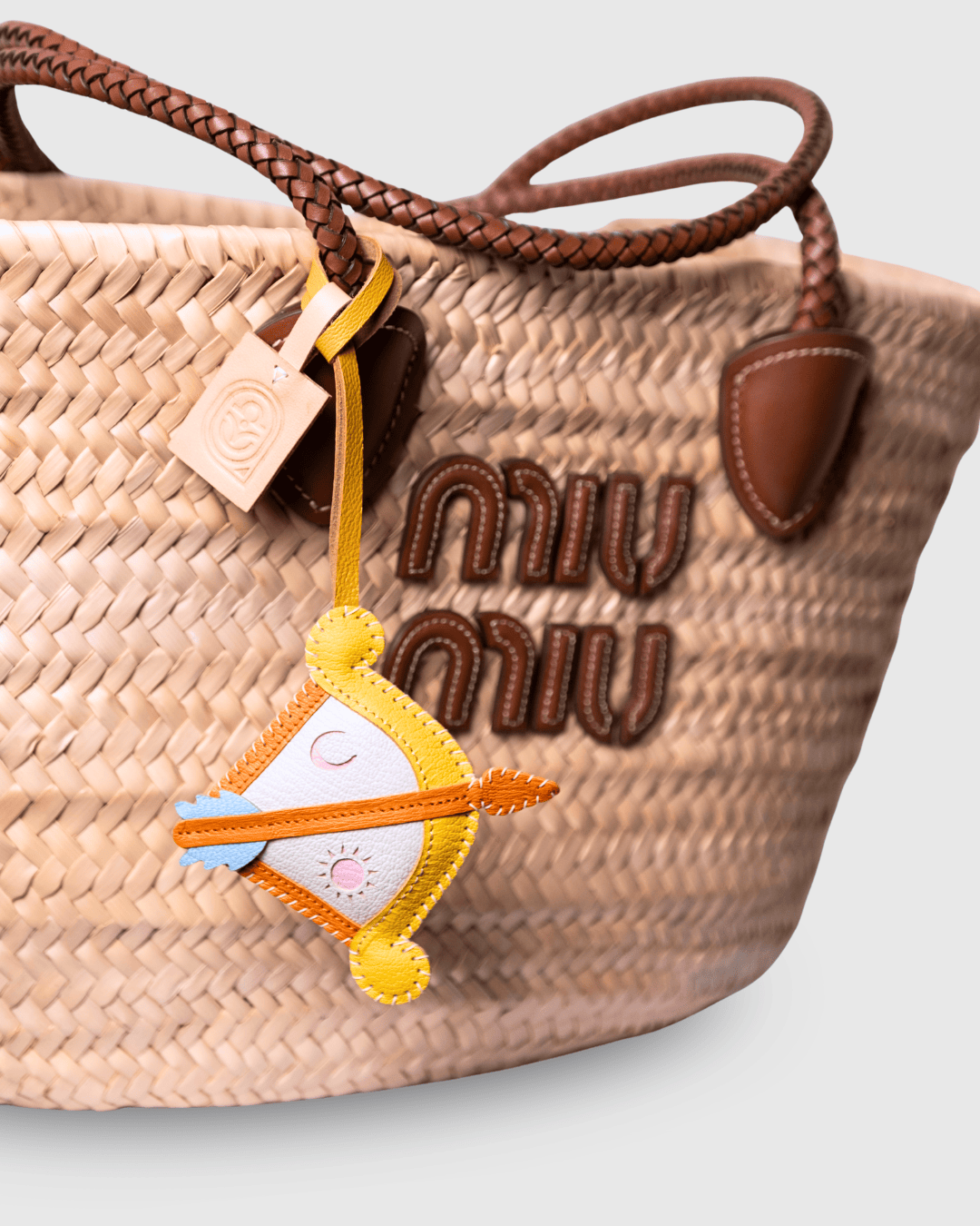 Woven handbag with decorative charm and logo.
