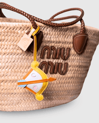 Woven handbag with decorative charm and logo.