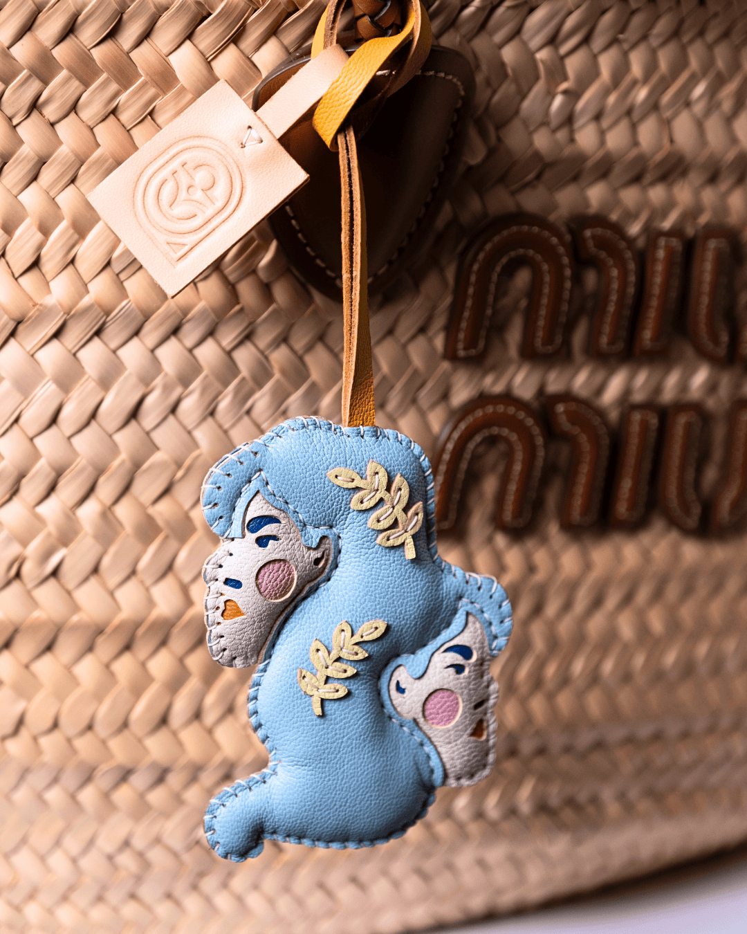 Blue charm hanging on woven bag.