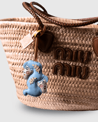 Woven straw handbag with leather accents and charm.