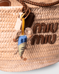 Straw tote bag with a lobster charm and brand logo.