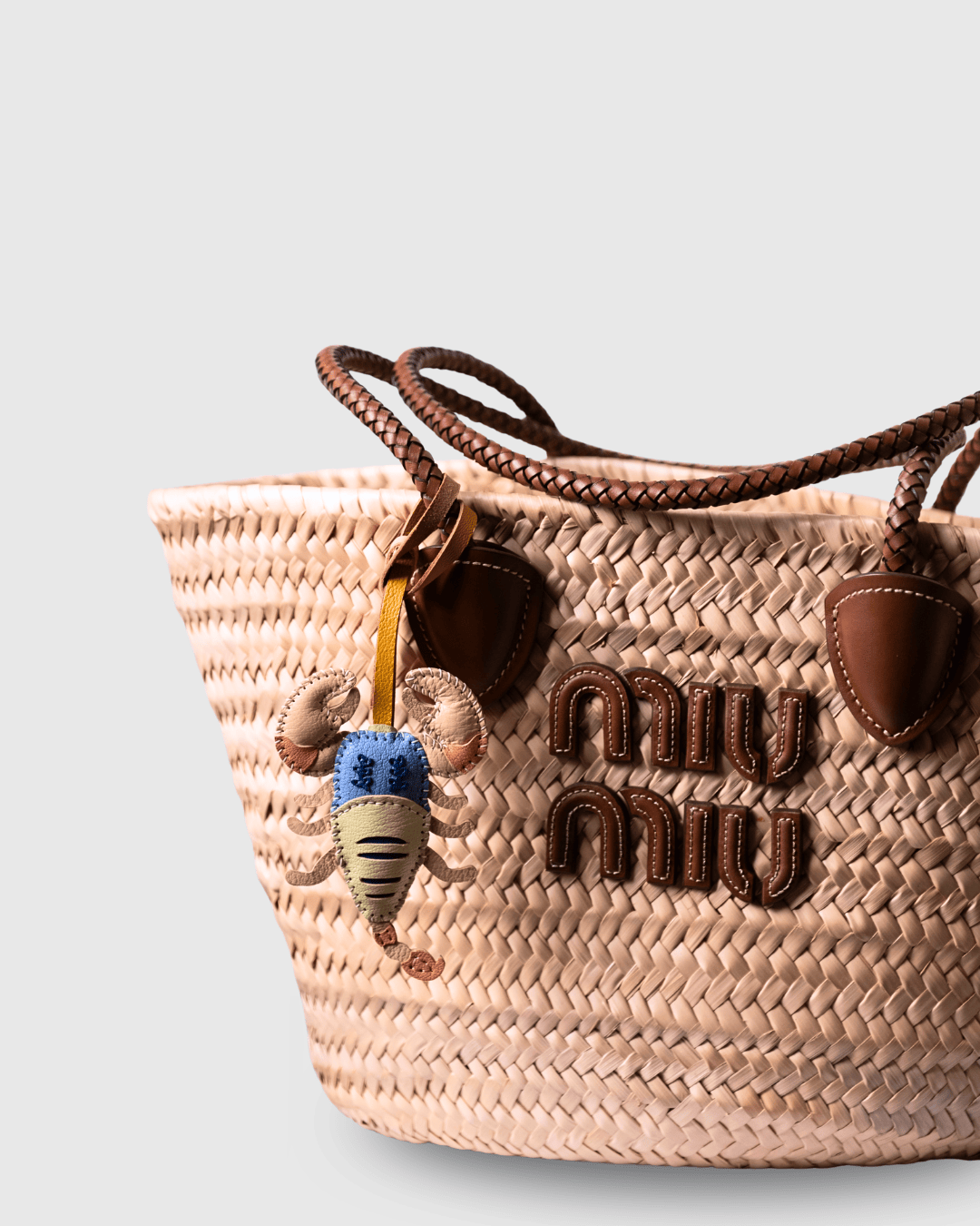 Woven bag with leather accents and a charm.