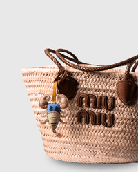 Woven bag with leather accents and a charm.