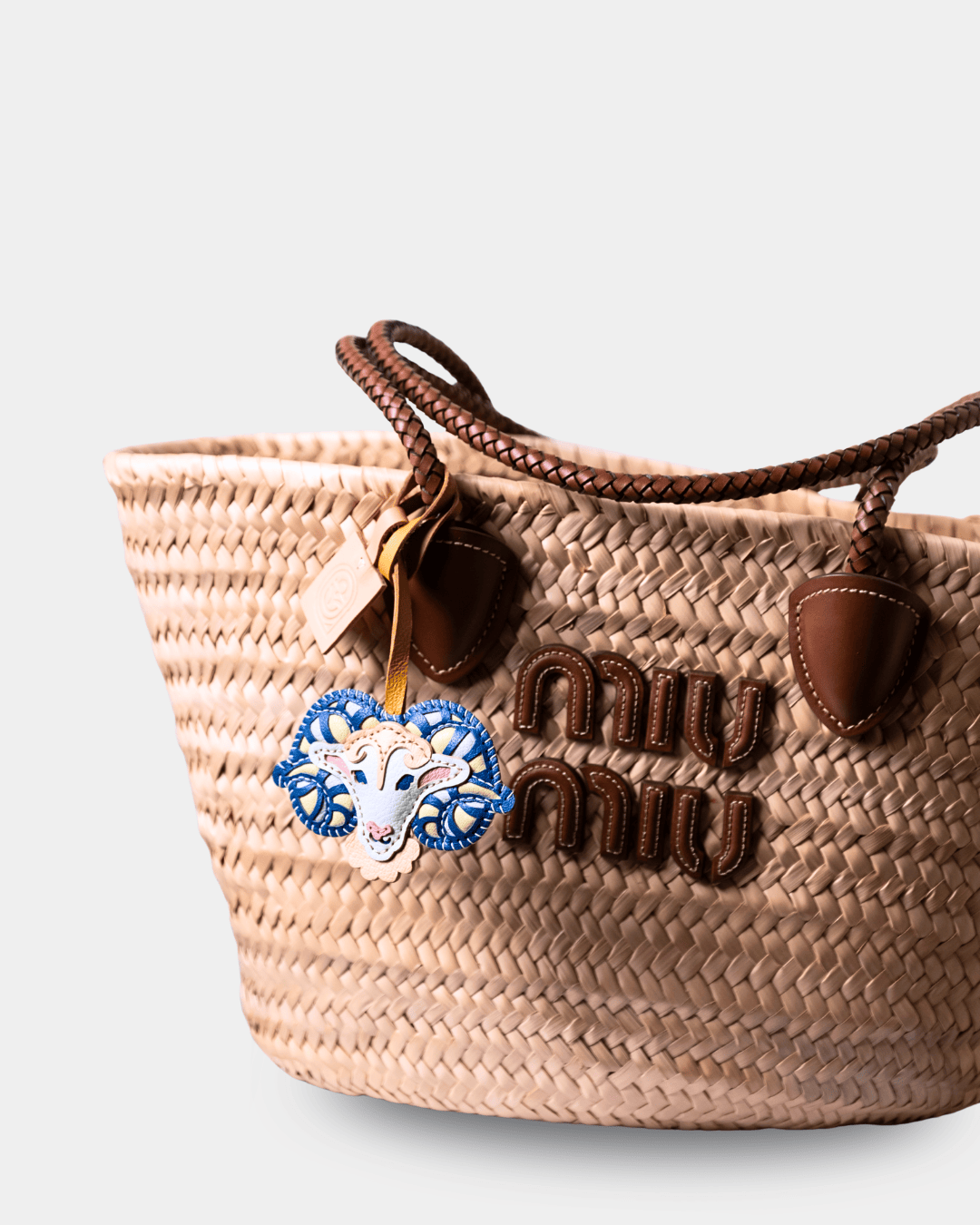 Woven handbag with leather accents and a goat charm.