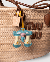 Woven straw bag with leather charm and logo.