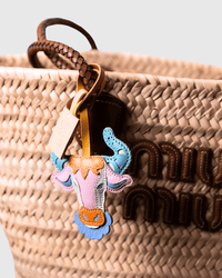 Woven bag with a cow-shaped leather charm.