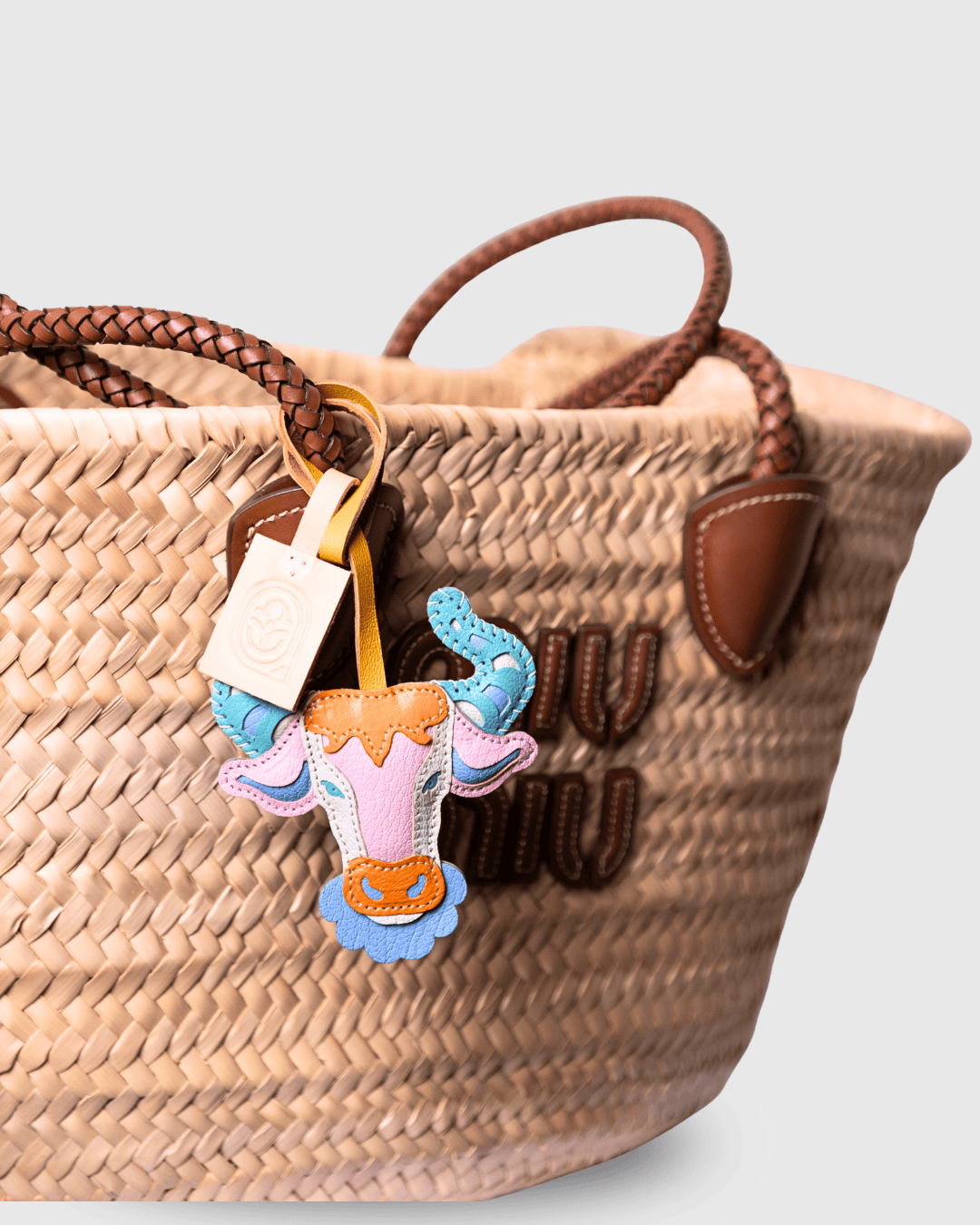 Woven straw tote bag with a bull charm.