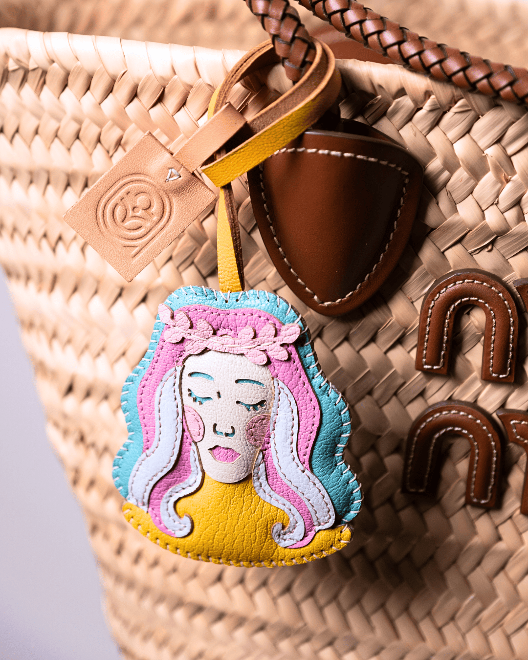 Woven basket with leather charms, including a face-shaped charm.