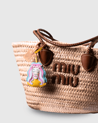 Straw tote bag with charm and logo detail.