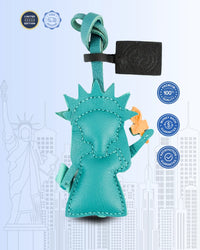 Turquoise goatskin leather bag charm resembling the Statue of Liberty on a light blue background with certification logos.