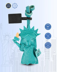 Turquoise Statue of Liberty leather bag charm on a light blue background with branding logos.