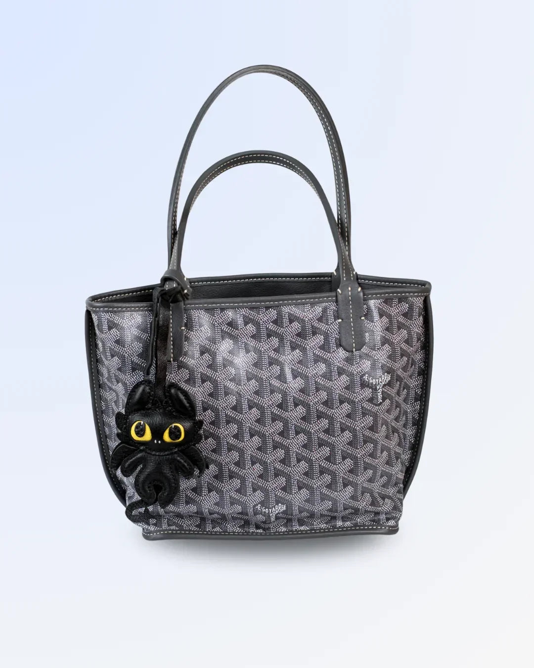 Black handbag with a toothless-shaped charm on a light blue background