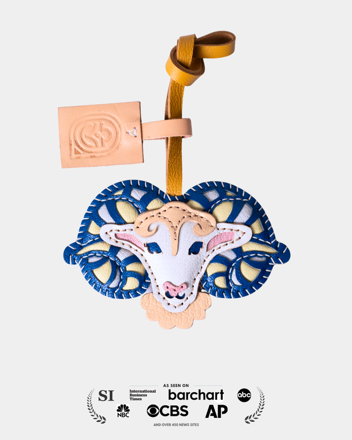 Decorative sheep head ornament with blue and yellow patterns on a white background