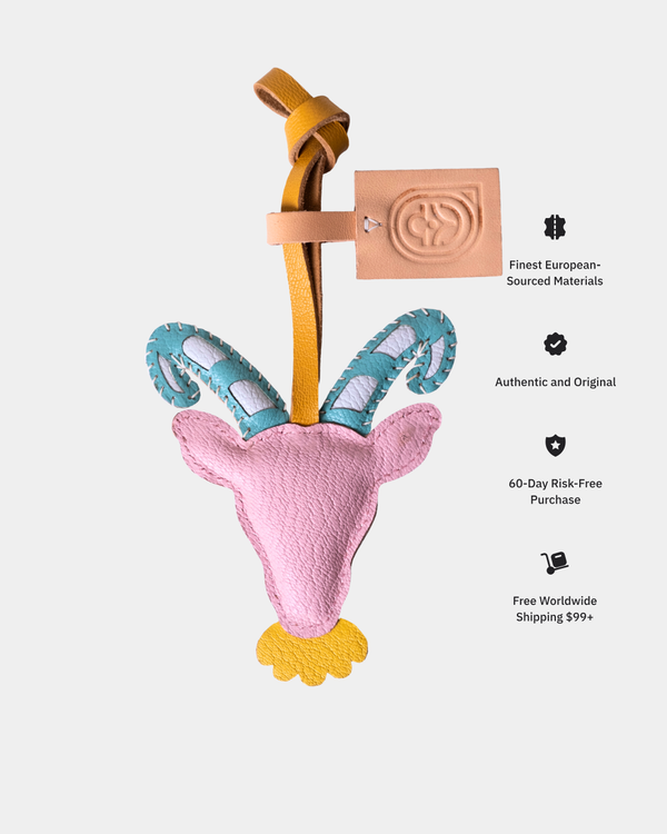 Pink ram head ornament leather charm with blue horns on a white background