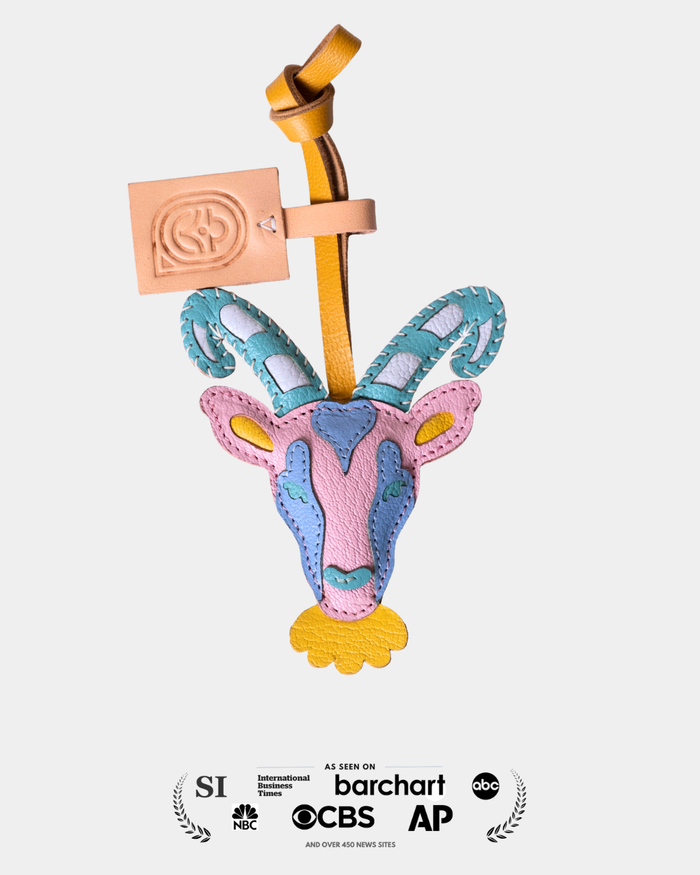 Colorful animal-shaped leather bag charm with a brand tag on a white background