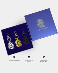 Three Q Charm keychains in a blue box with branding on a white background
