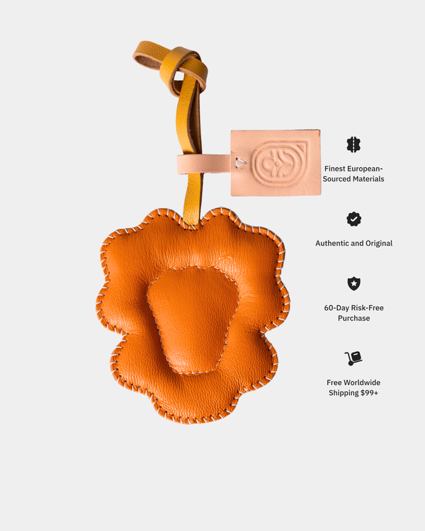 Orange leather leo-shaped keychain with a brand tag on a light gray background