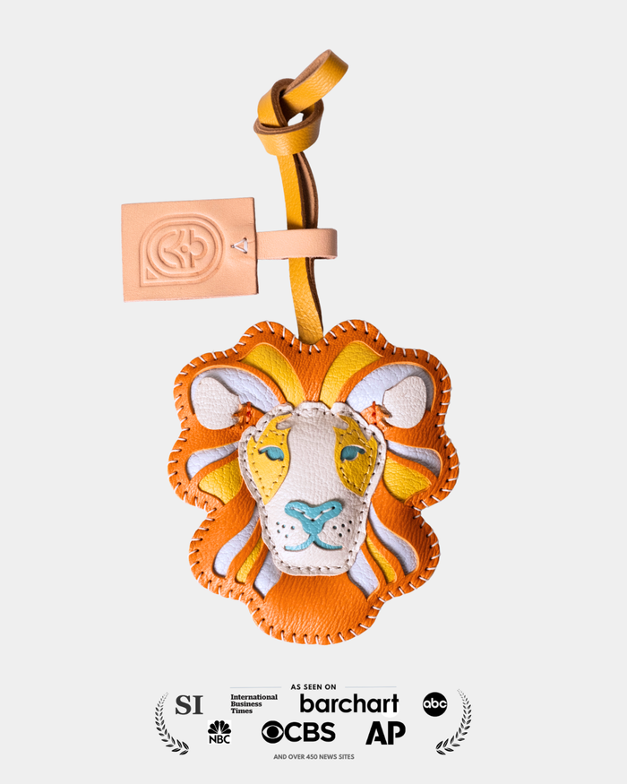 Lion-shaped keychain with a strap on a light gray background